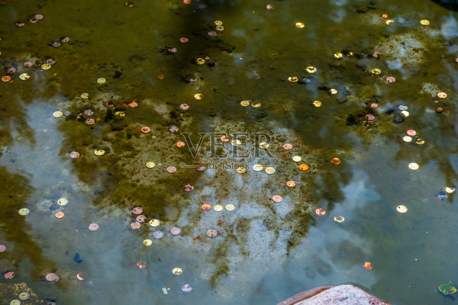 许愿币散落在浅水喷泉的水下。照片摄影图片