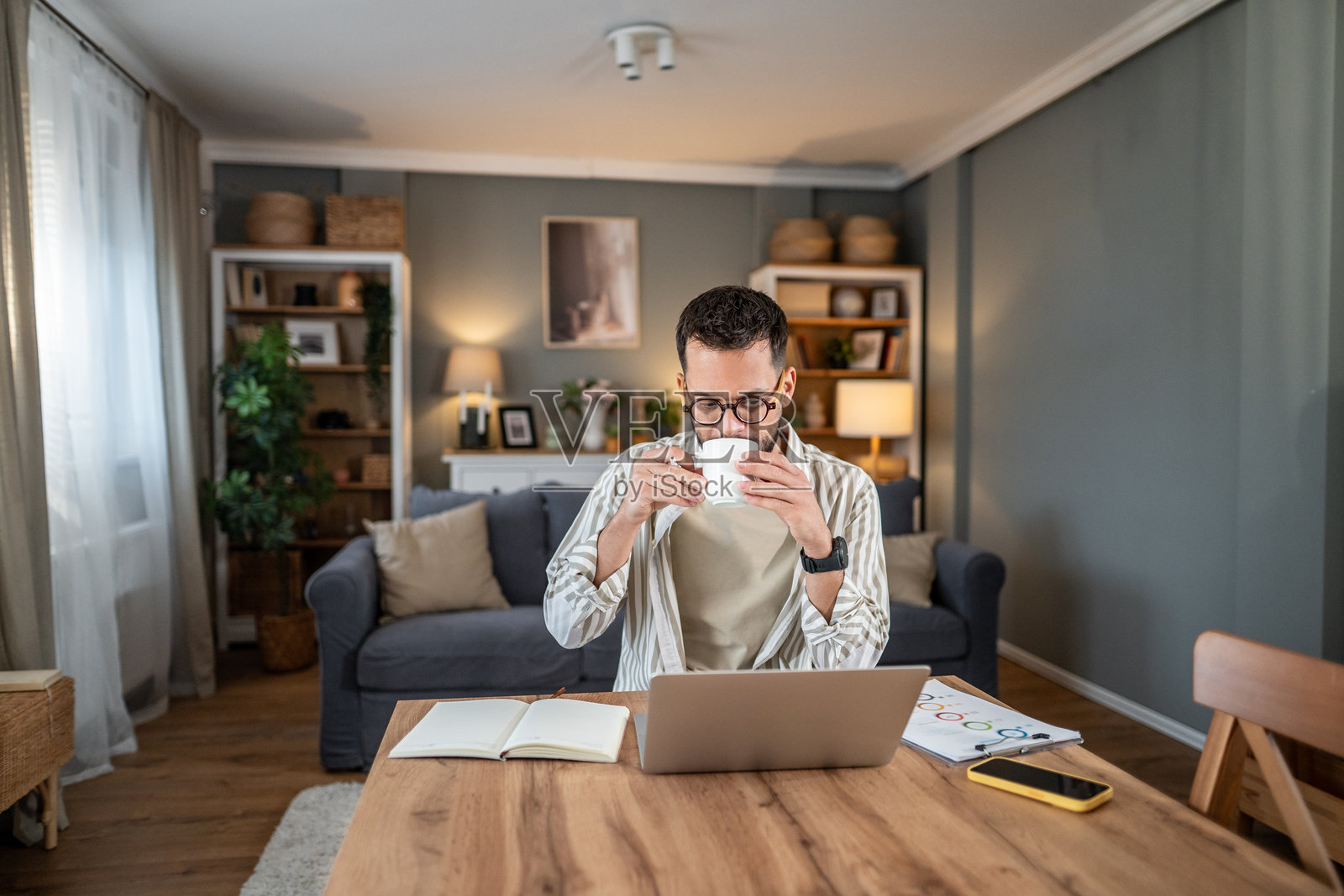 男人在家喝咖啡，使用笔记本电脑工作照片摄影图片