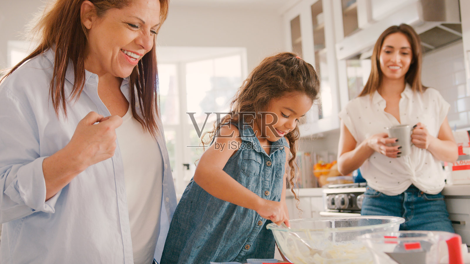 厨房里三代女性家庭成员在家一起烘焙，享受欢乐时光照片摄影图片