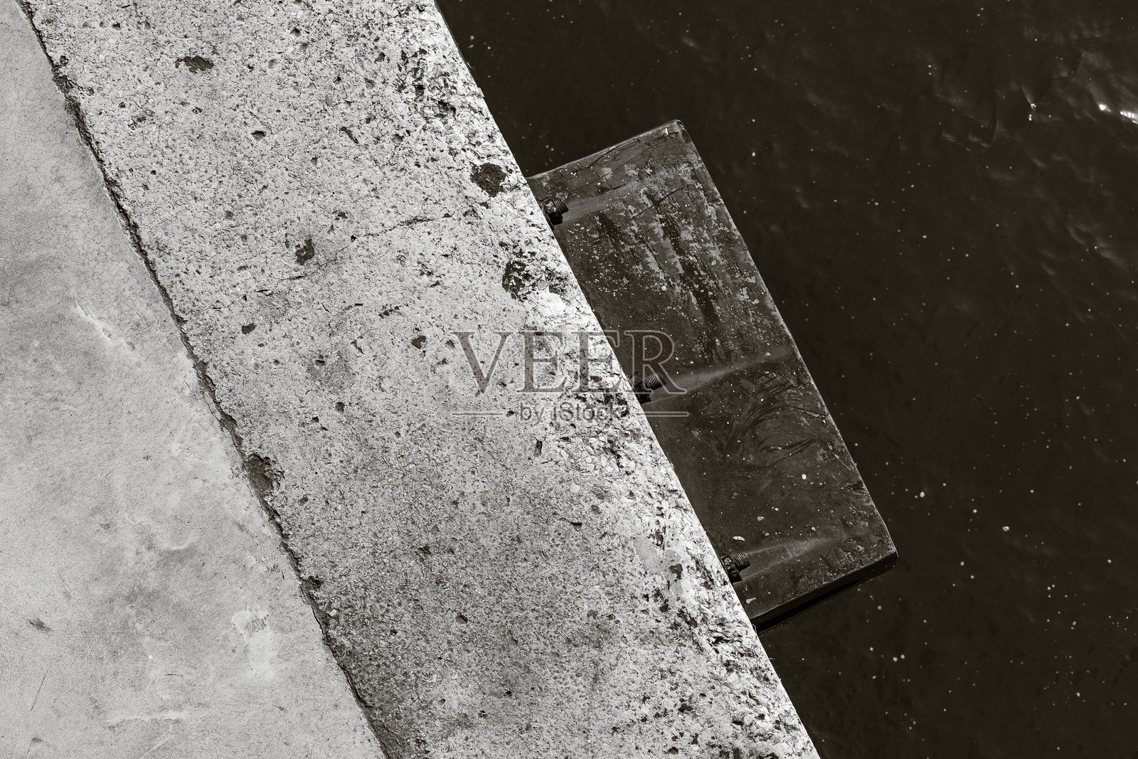 极简抽象黑白摄影，展现建筑细节。图形化构图，突显粗糙混凝土码头与深色水面的纹理对比。照片摄影图片