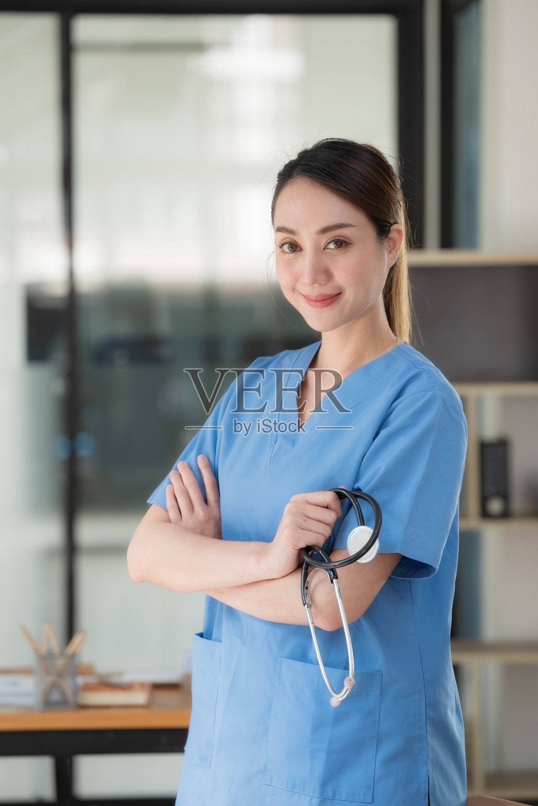 一位身穿蓝色外套、佩戴听诊器的亚洲美女医生，医学概念，半身像。一位女性医务工作者正看着镜头微笑。照片摄影图片