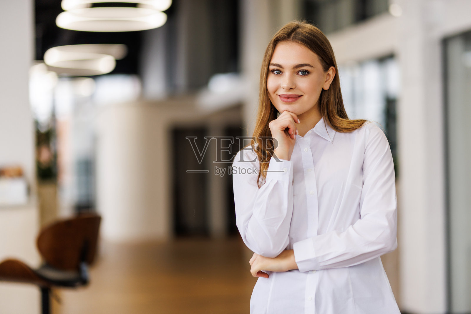 一位美丽的职业女性，双手交叉，在办公室里对着镜头微笑照片摄影图片
