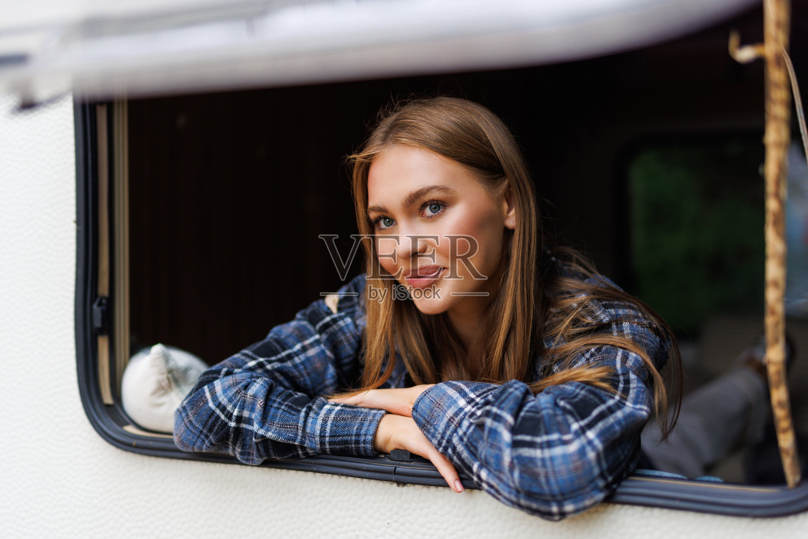 早晨，一位女性从露营车窗外眺望。照片摄影图片