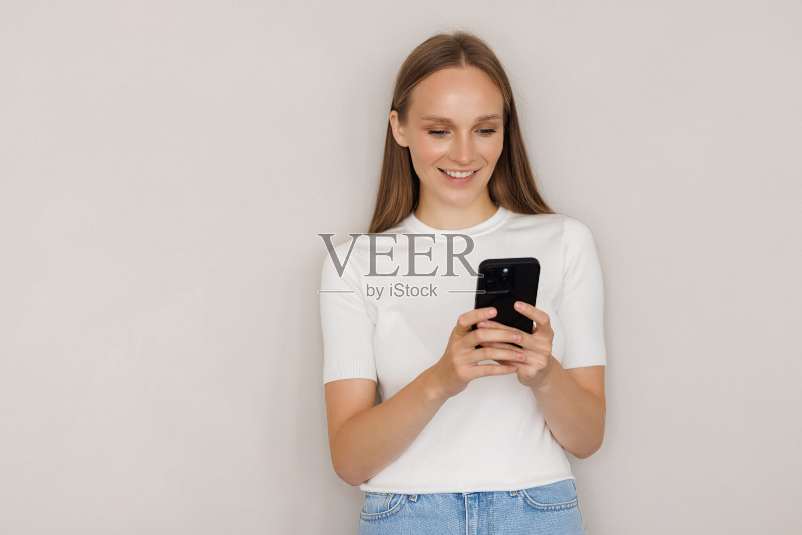 一名面带微笑的女子手持智能手机，背景为白色，肖像照照片摄影图片