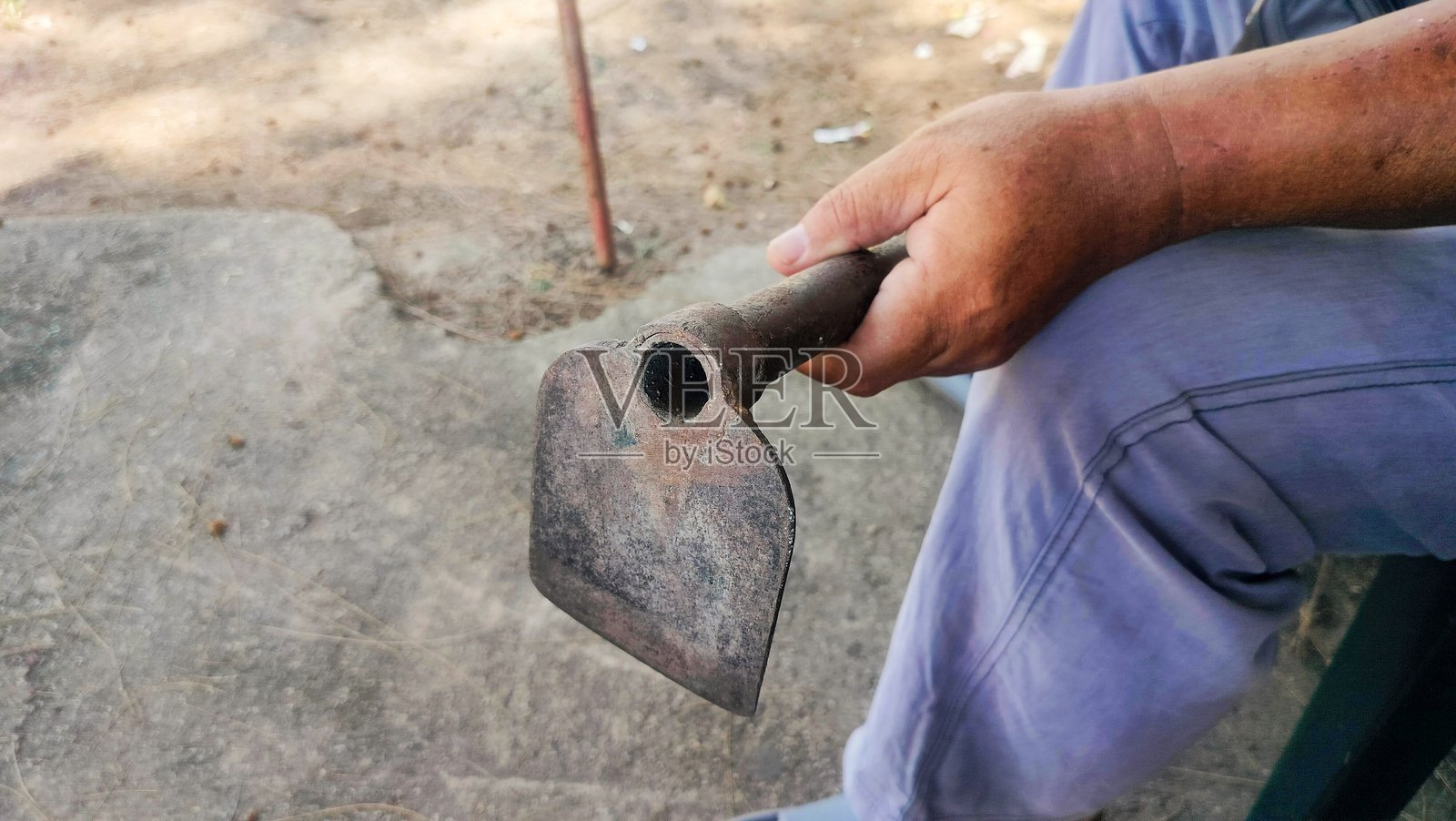 农民正用铁锄头耕地，一个人拿着锄头。照片摄影图片