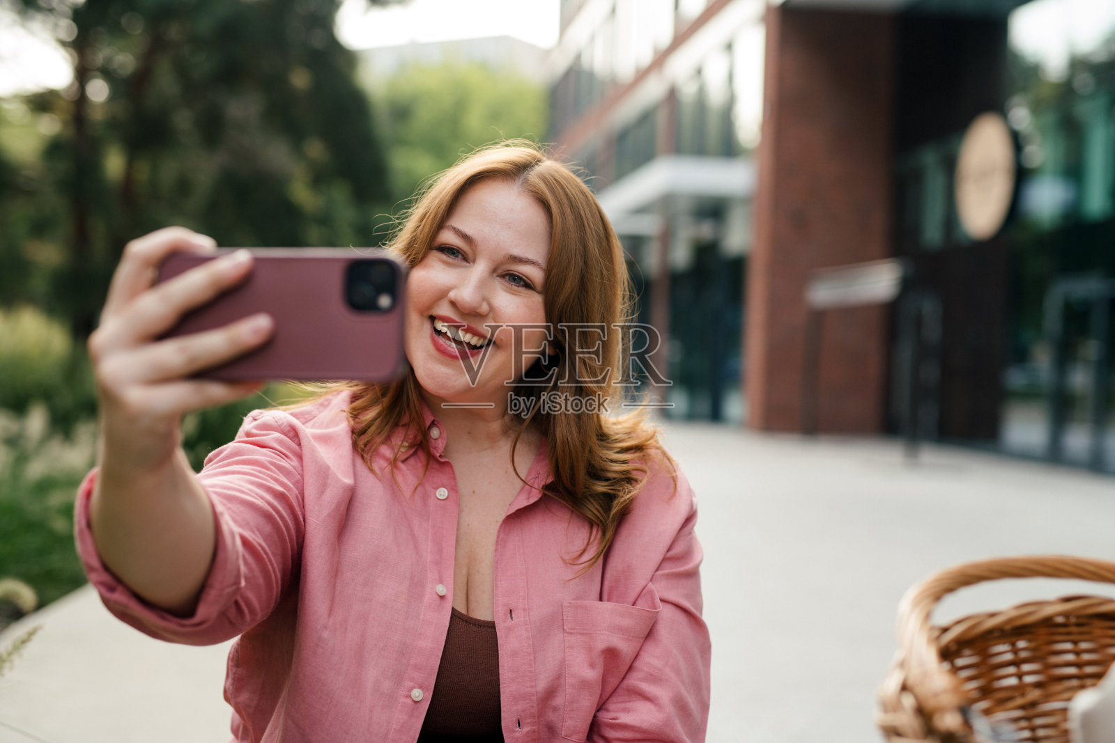 身材丰满的女性在公园进行视频通话。照片摄影图片