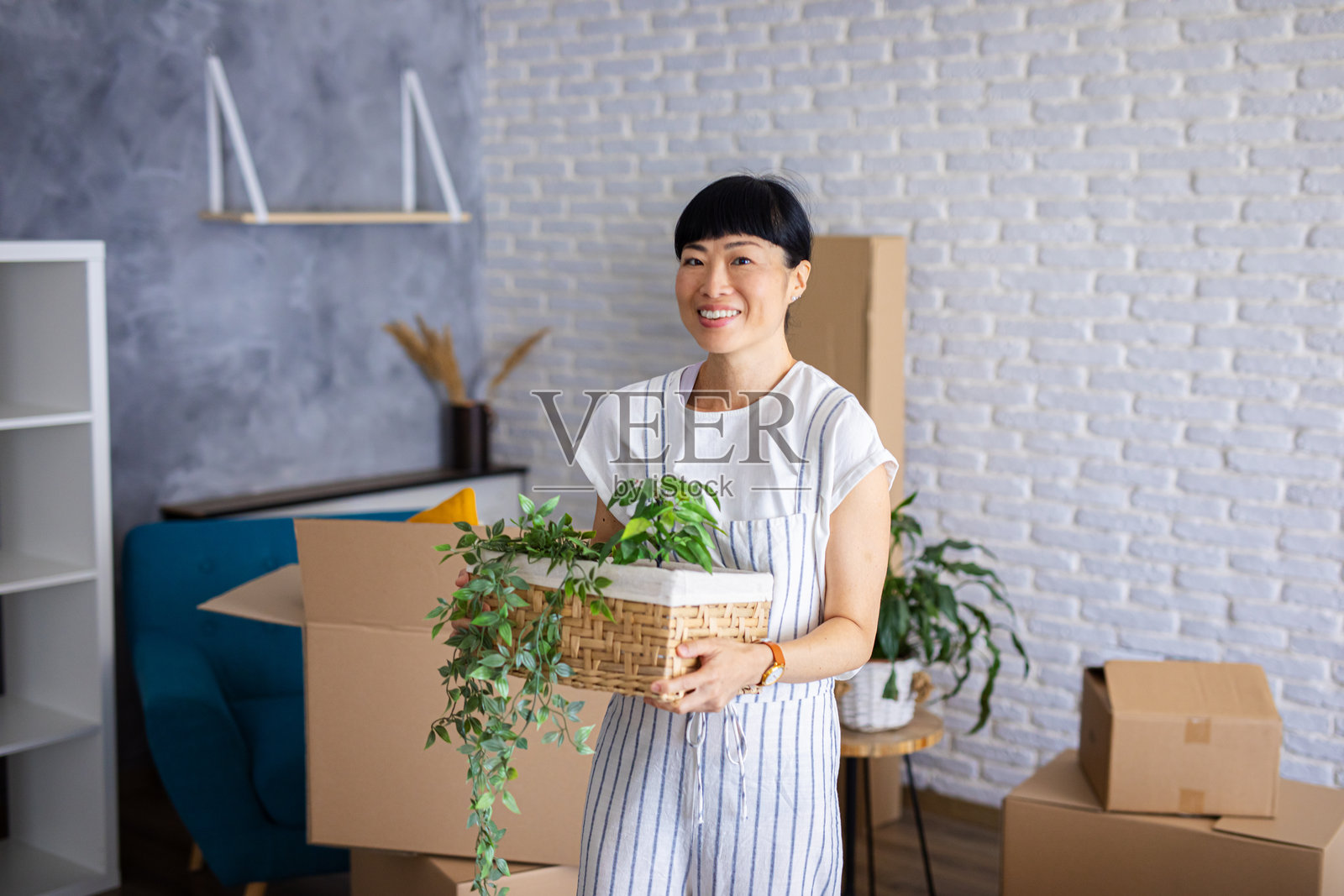 快乐的女人被纸箱包围，正在新家拆箱入住。照片摄影图片