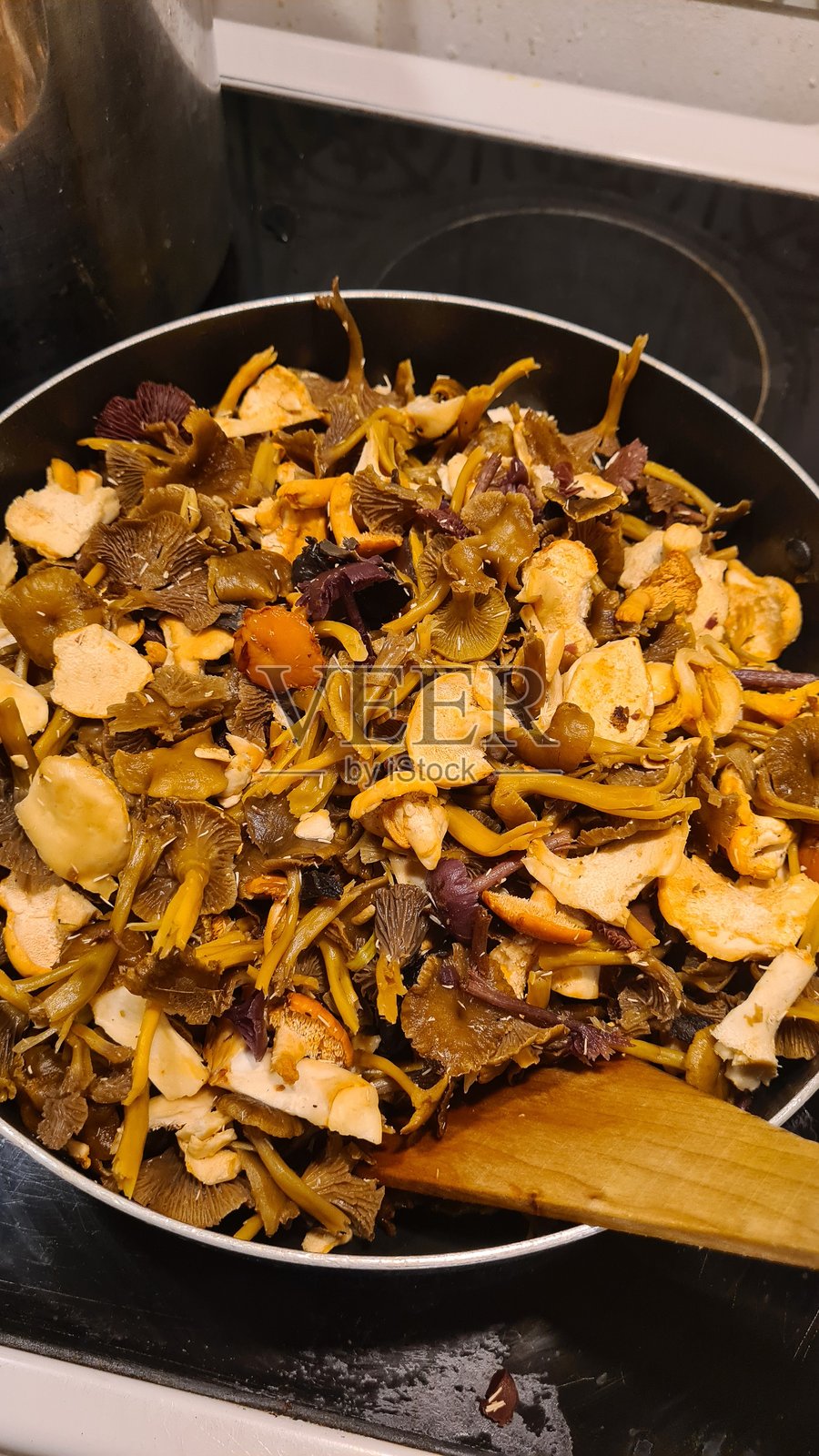 烹饪多种野生小蘑菇（冬/黄牛肝菌、齿状牛肝菌/猪蹄菌、金牛肝菌和黑喇叭菇/死神喇叭菇）照片摄影图片