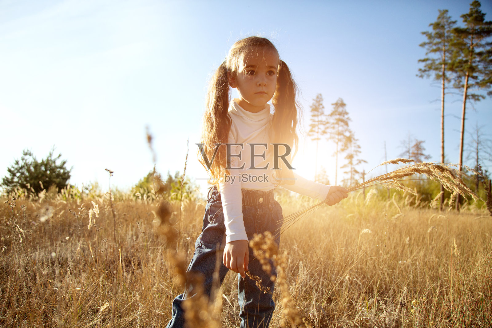 夕阳余晖中，一个小女孩在花田中自由自在地奔跑。照片摄影图片