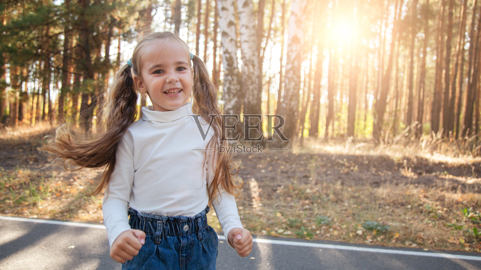 快乐的小女孩在日落时分漫步公园，玩得很开心照片摄影图片