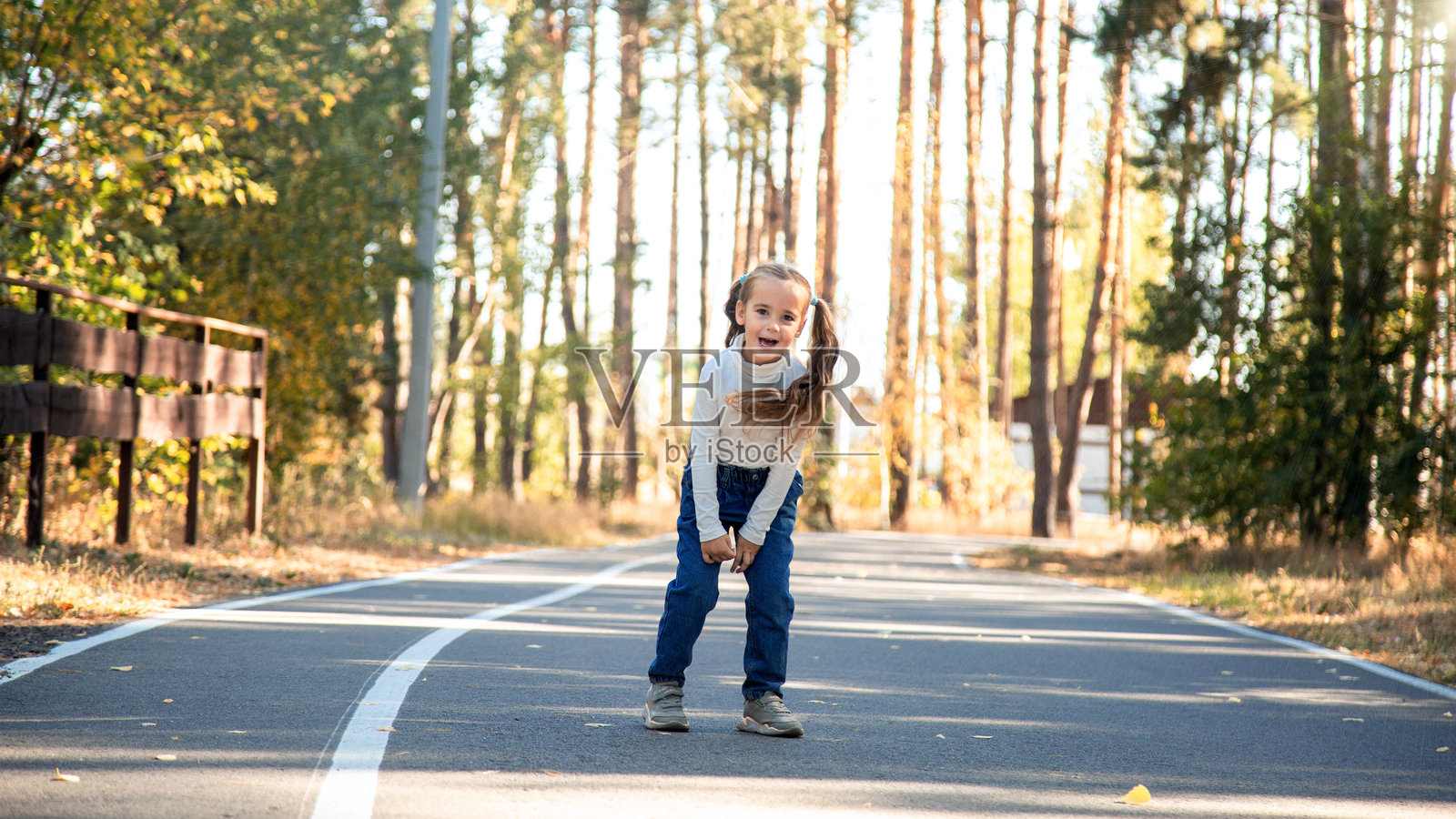日落时分，学龄前小女孩在公园里散步照片摄影图片