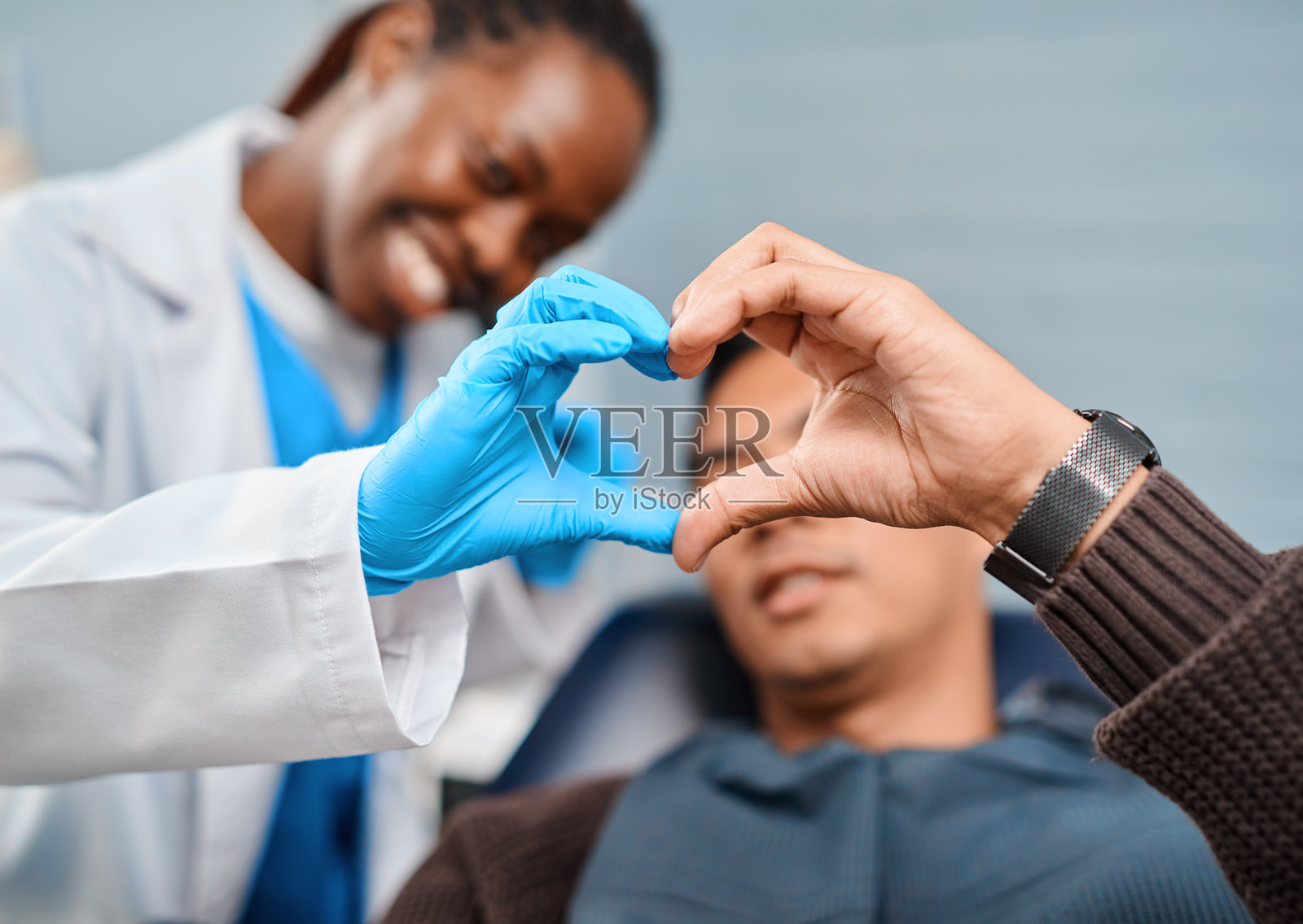 黑人牙医在看牙时为亚洲患者咨询，并做出心形手势照片摄影图片