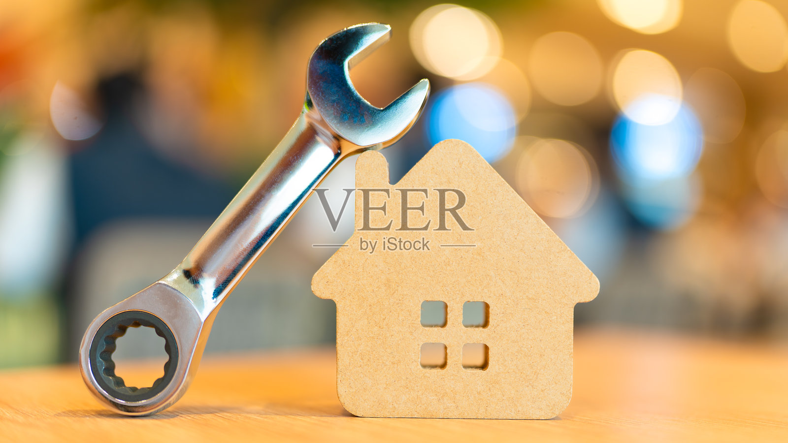 工具扳手靠着木制房屋模型，象征着房屋维修、保养、翻新、物业管理或房地产服务。非常适合建筑、住房和杂工业务的概念。照片摄影图片