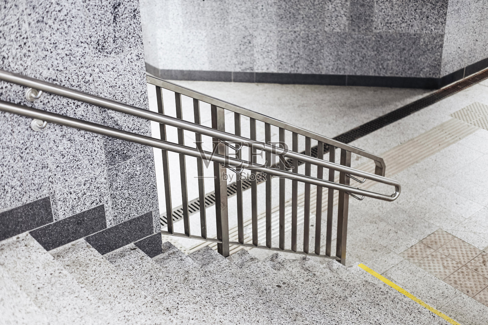 室内楼梯，配有不锈钢扶手和花岗岩墙壁。现代公共建筑内部。安全的建筑细节，带有栏杆。照片摄影图片