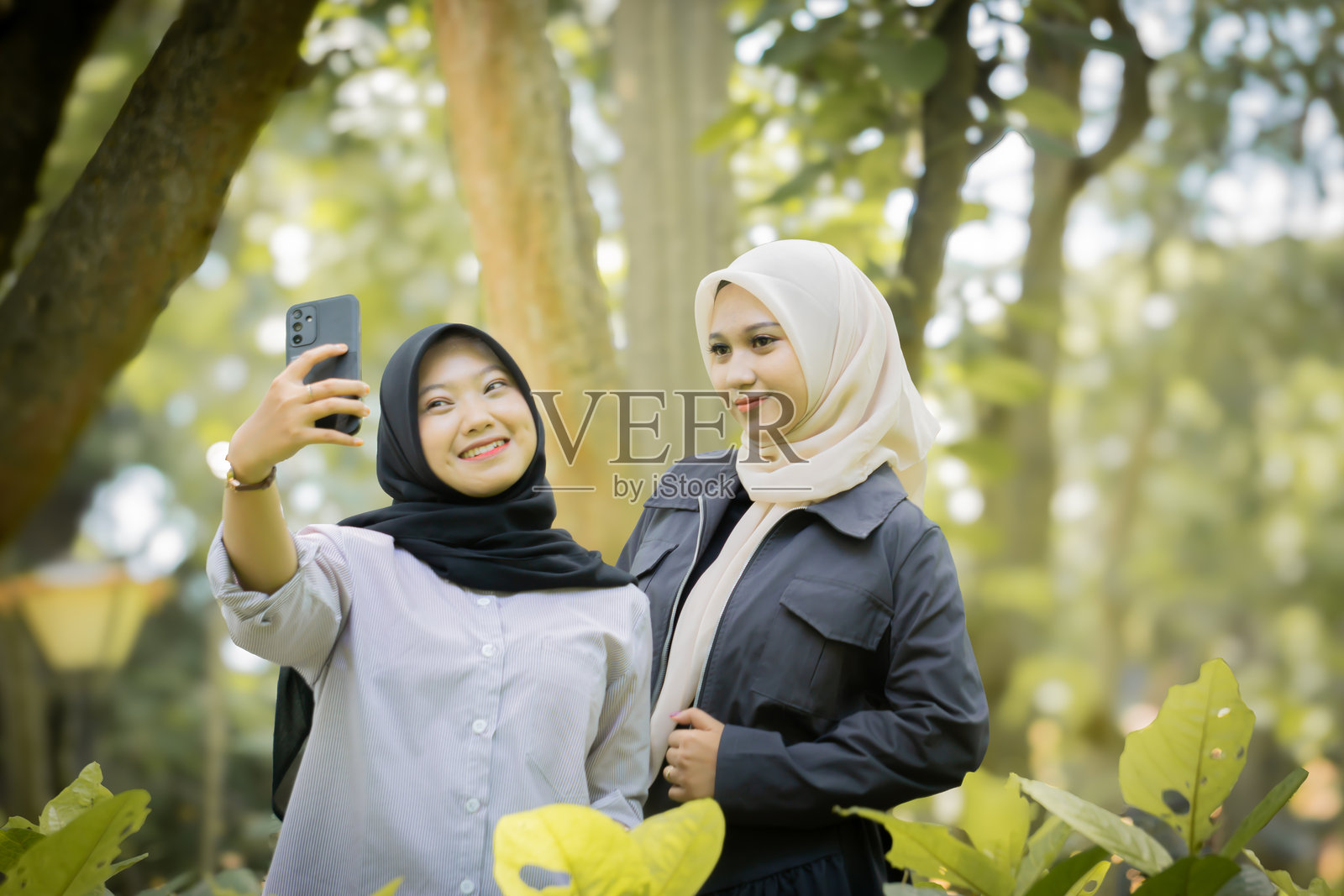 两个漂亮的亚裔姐妹在公园里一起自拍。照片摄影图片