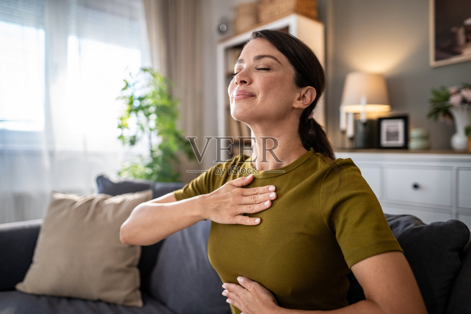 女子在家中进行深呼吸练习以放松身心，促进健康。照片摄影图片