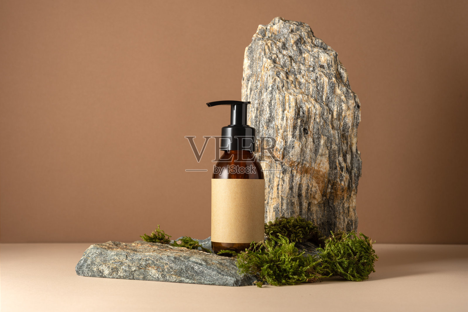 石头讲台上的简约琥珀色化妆品瓶泵和空白牛皮纸标签模型照片摄影图片