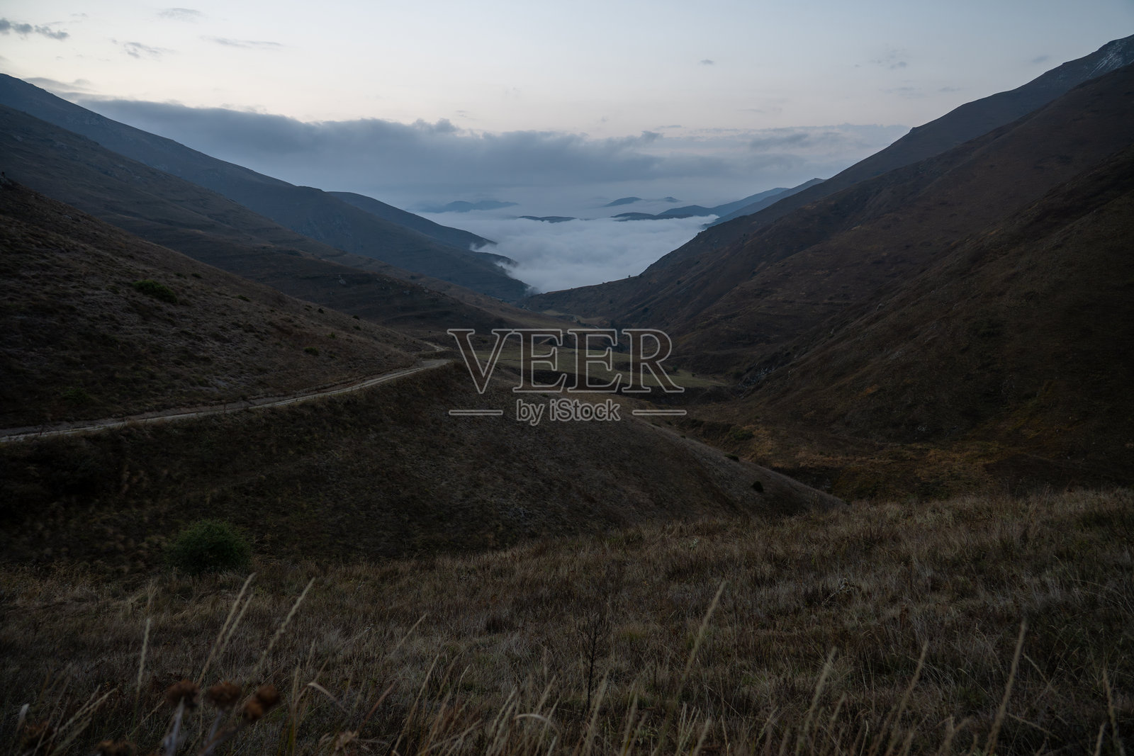 日出时宁静的山景，有云海和蜿蜒的道路照片摄影图片