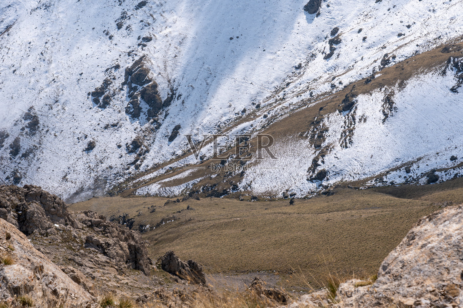 干枯的草和雪交融在崎岖的山坡上照片摄影图片