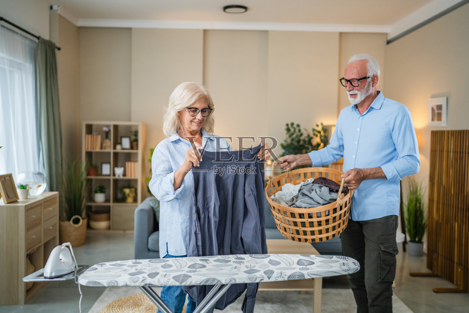 老年夫妇分担家务，一同熨烫衣物照片摄影图片
