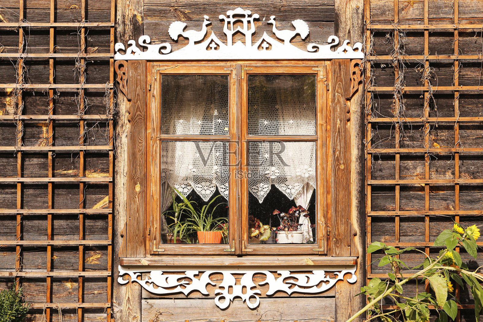 质朴木屋的装饰窗户。传统雕刻窗框配蕾丝窗帘。照片摄影图片