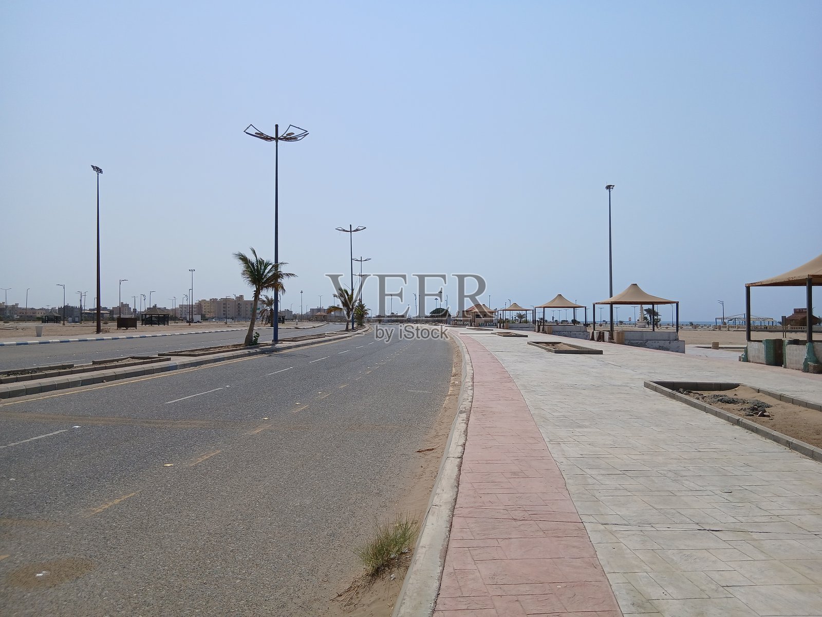 清晨红海滨海大道的道路，有灯柱和遮阳伞。照片摄影图片