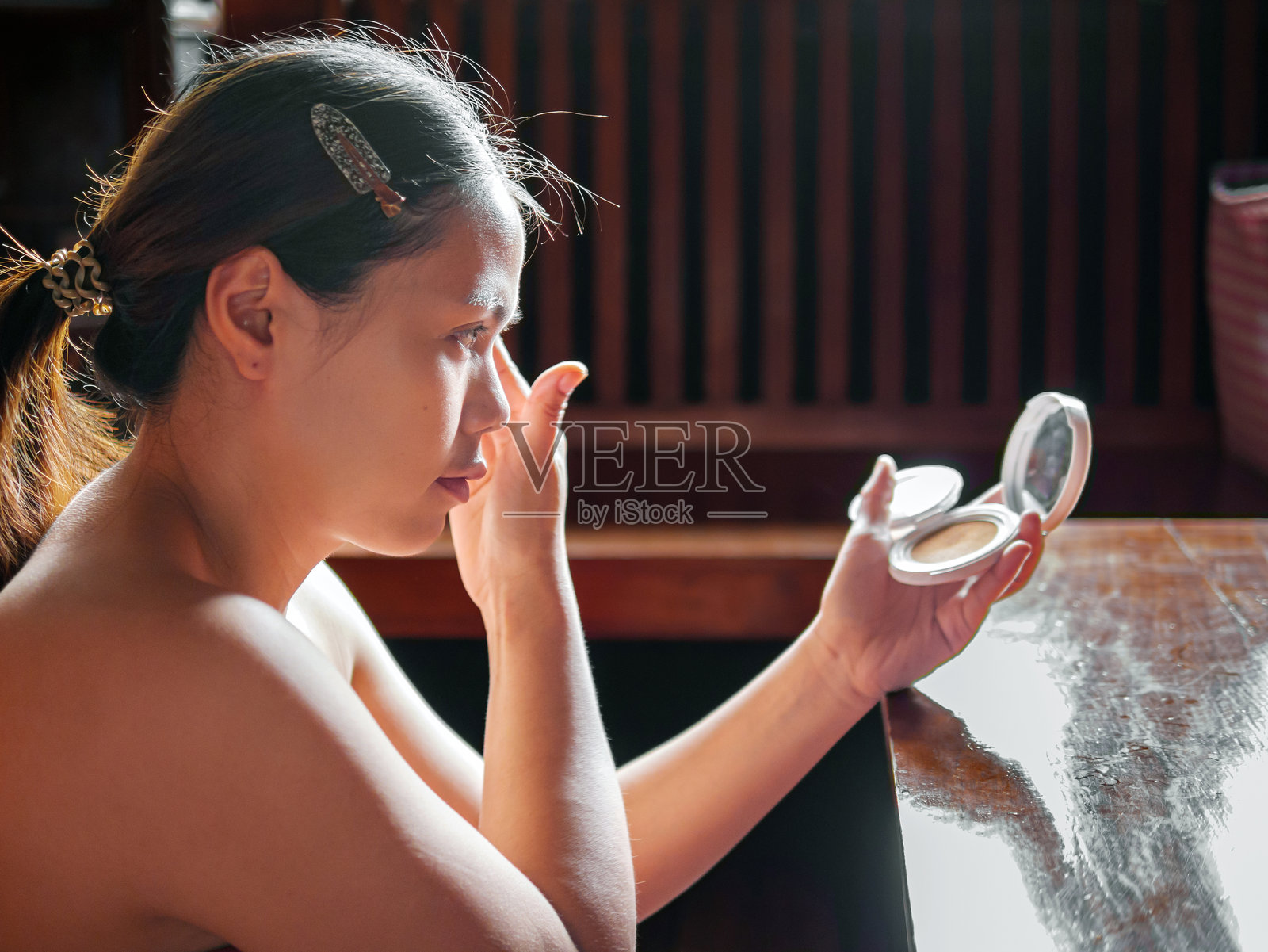 美容与护肤，一位美丽的女子在化妆时涂抹半透明的散粉，一位亚洲女性手持粉饼并涂抹在脸上照片摄影图片