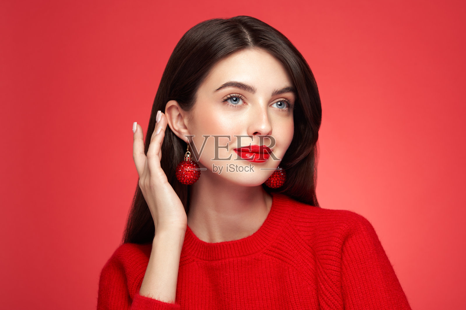 身穿休闲装的年轻女子，在红色背景前摆出姿势照片摄影图片