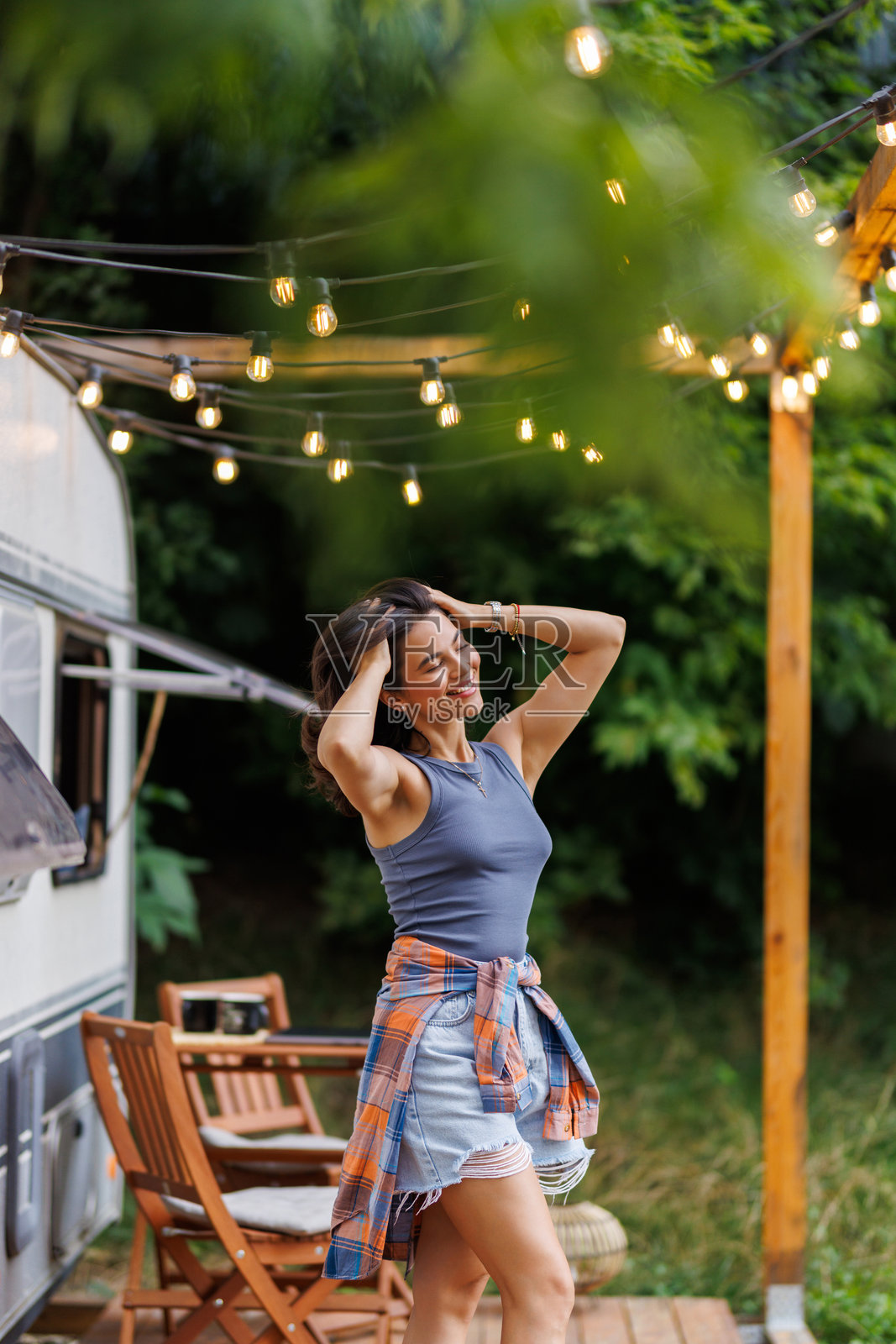 美丽的年轻女子在日落时分，开着她的露营车在公路旅行中休息照片摄影图片