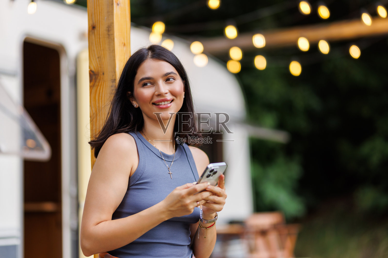 年轻女子在度假时，在租来的露营车前使用手机照片摄影图片