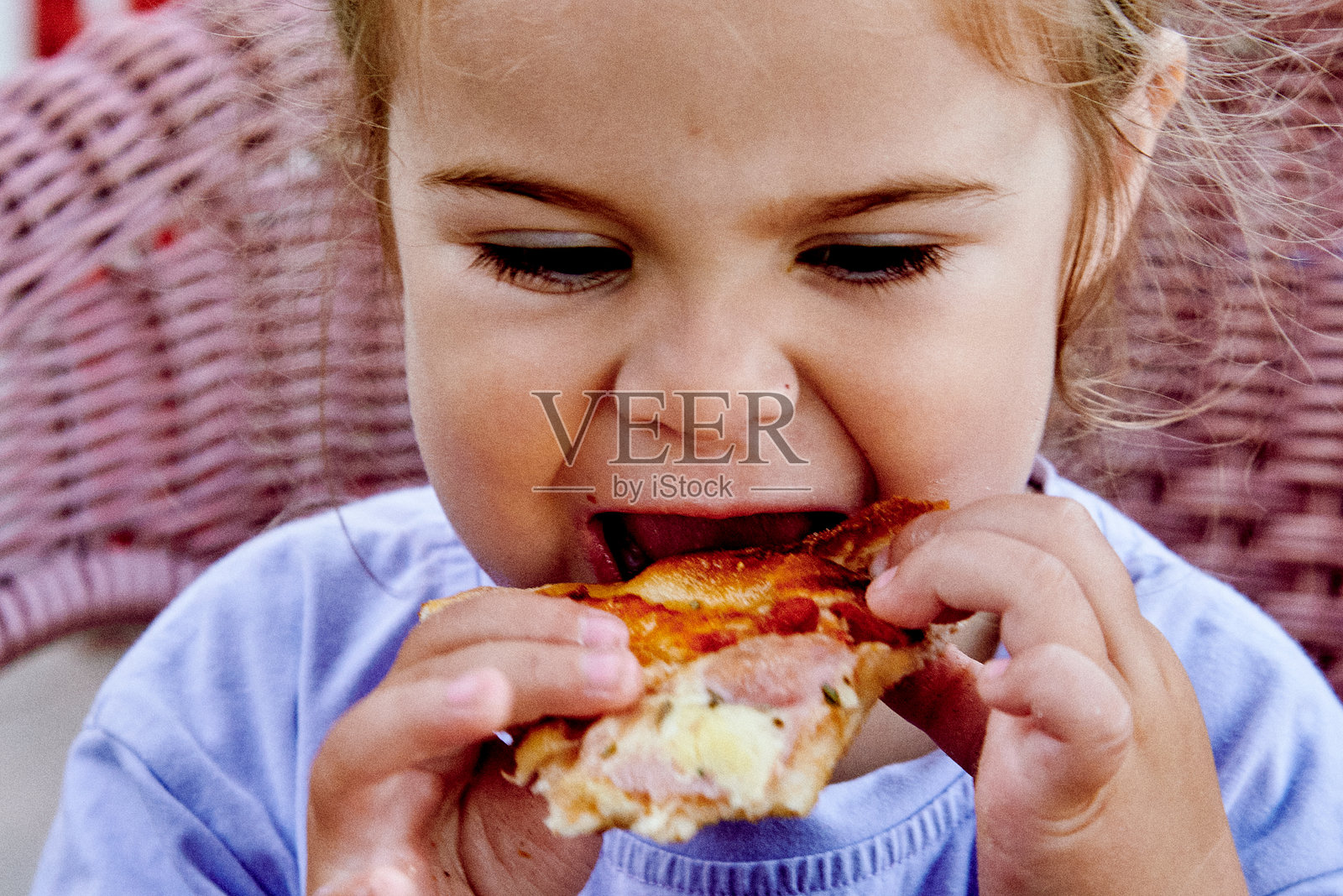 小女孩吃着奶酪披萨，脸上露出有趣的表情，特写镜头。照片摄影图片