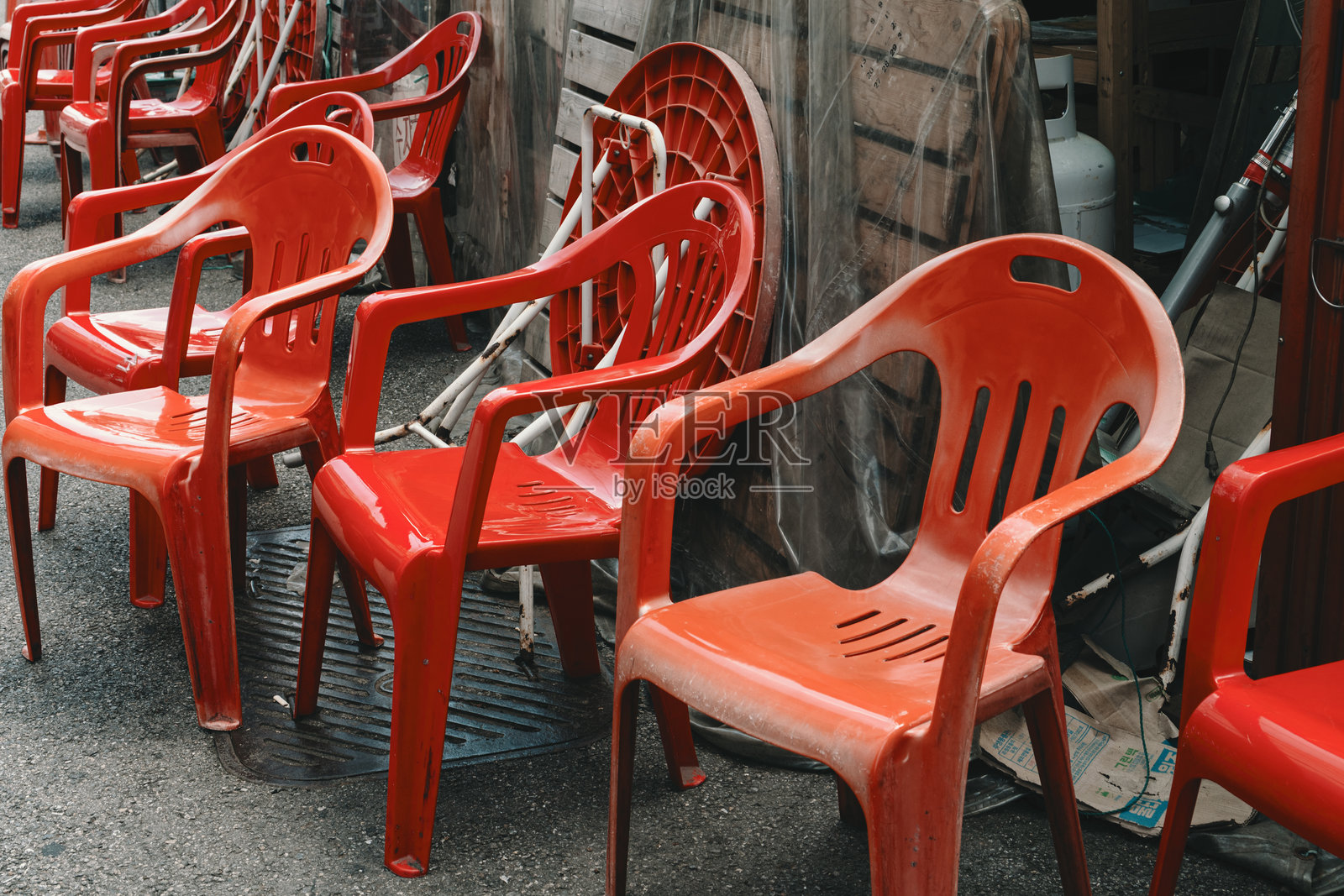 城市街道上，一排排空置的红色塑料椅子放在湿漉漉的路面上。照片摄影图片