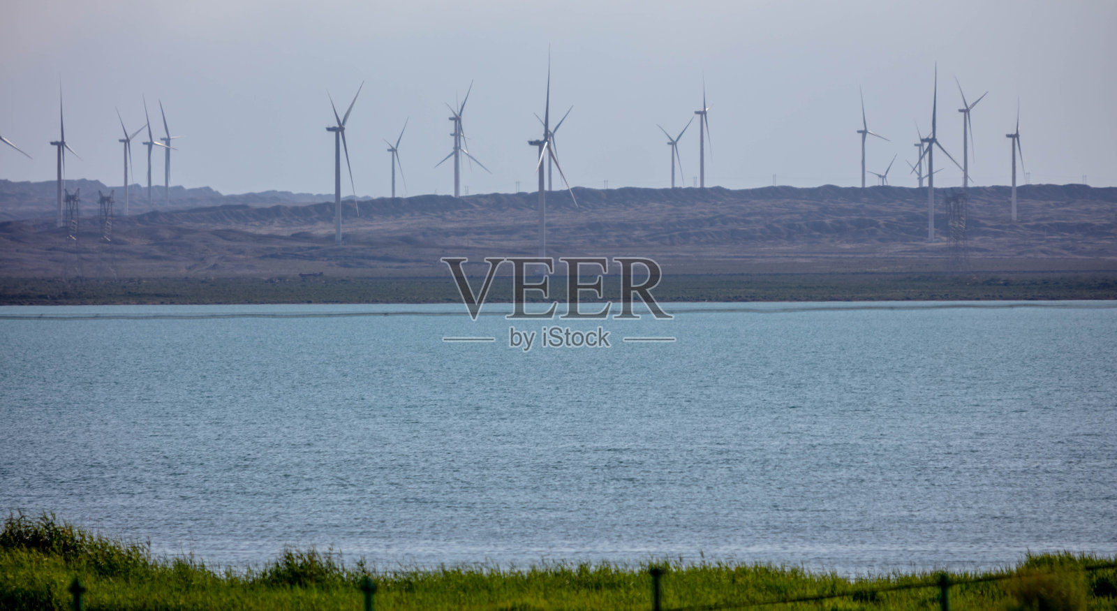 风力涡轮机密集地分布在湖边照片摄影图片