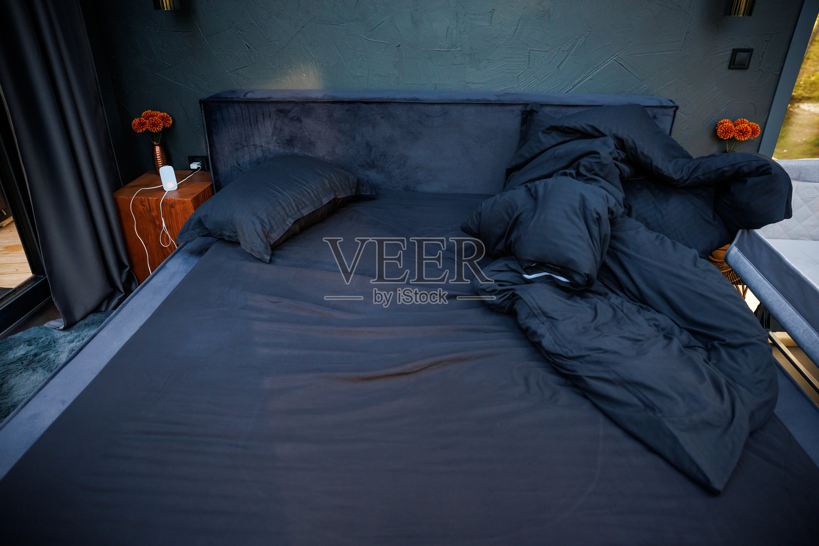 现代卧室，深色墙壁，黑色床品，木质床头柜照片摄影图片