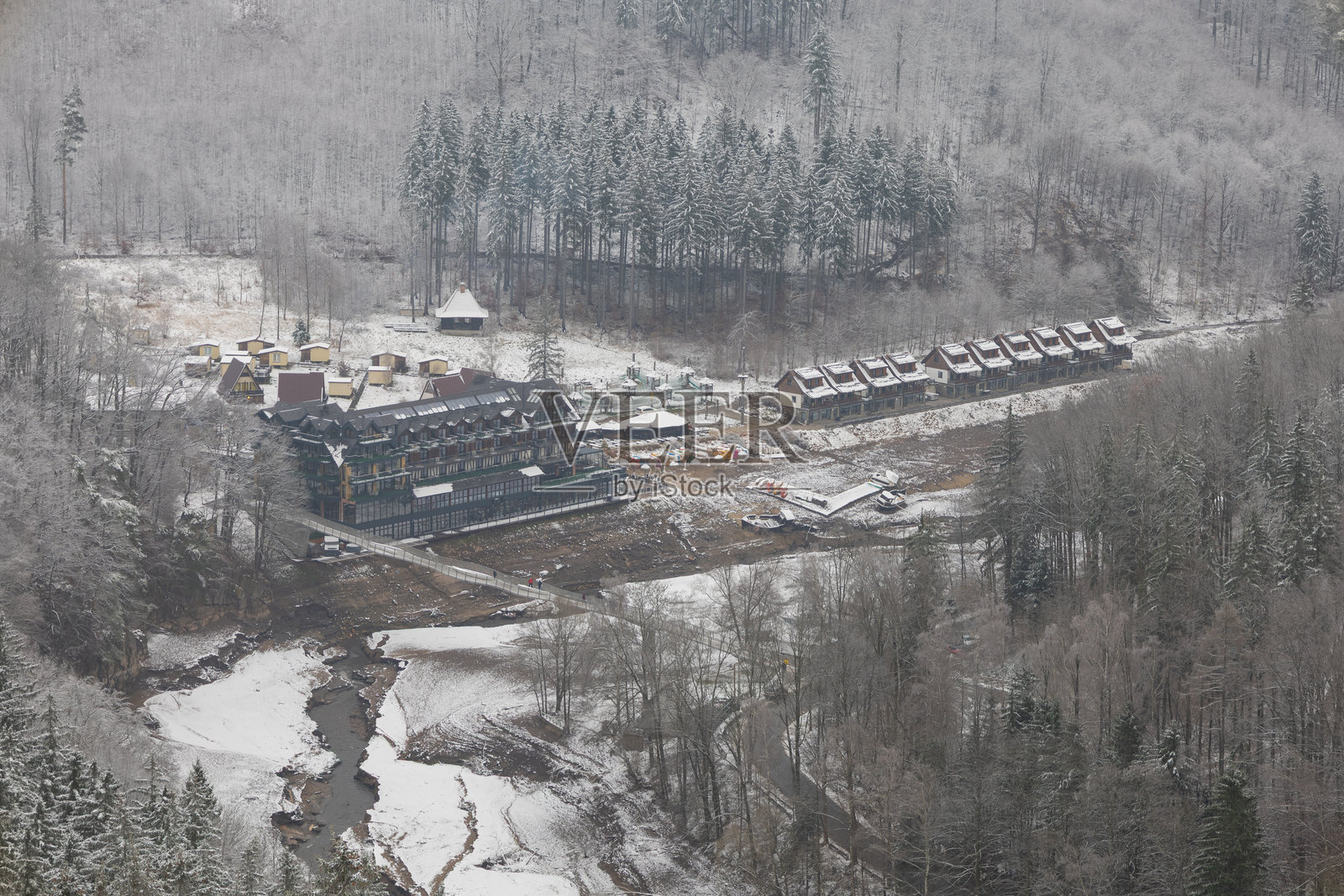 冬季山脉中，浅河岸边的酒店群照片摄影图片