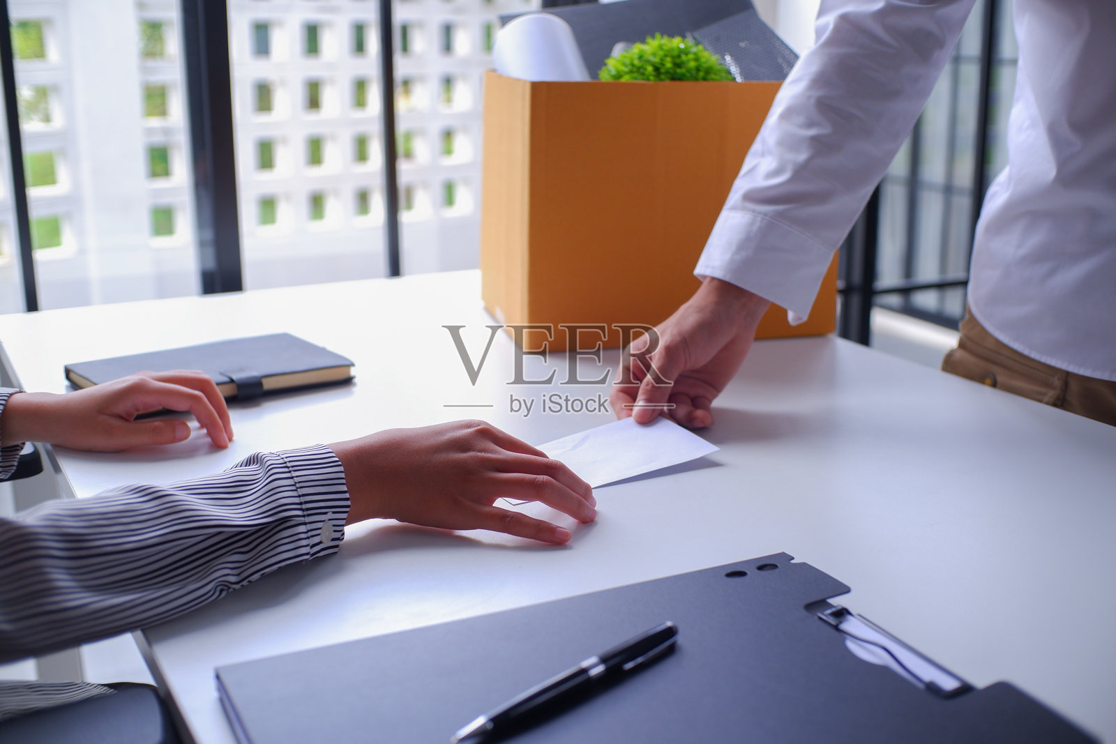 特写：男员工递交辞职信（白色信封），给经理或人力资源部，当他决定辞职时。照片摄影图片