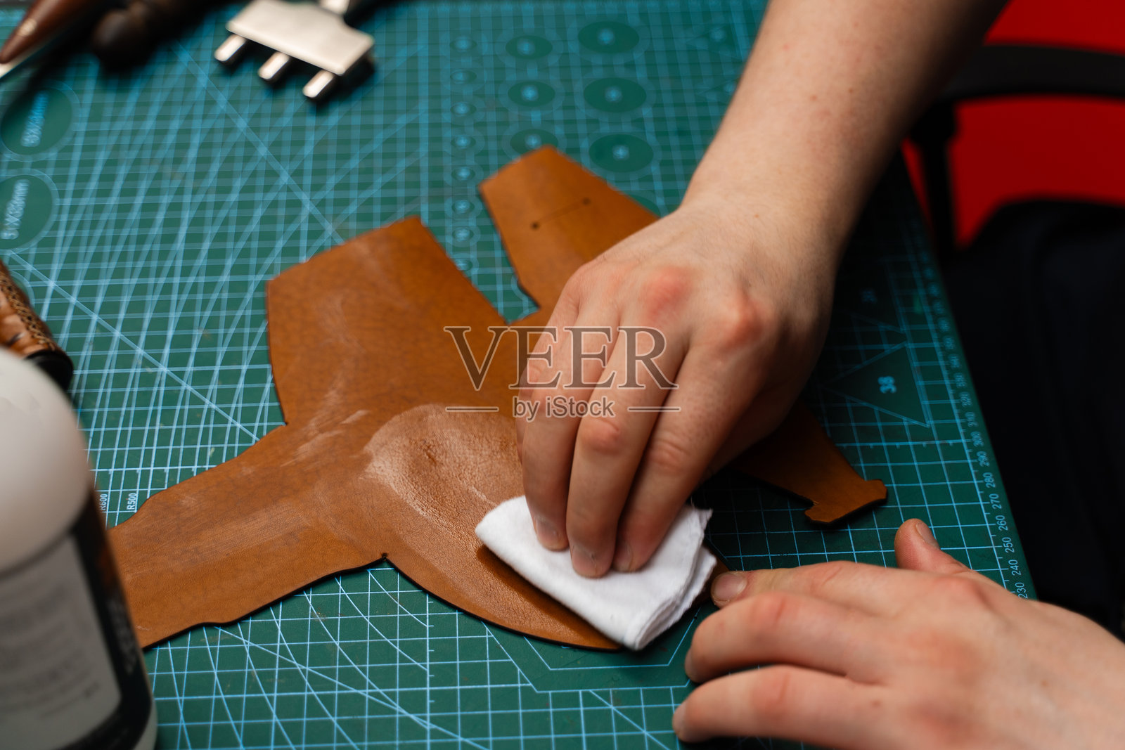 用布擦拭皮革进行护理，恢复光泽、弹性和强度。皮革染料或护理剂的涂抹可保护表面和颜色。用布将护理剂或染料涂抹在皮革上。照片摄影图片