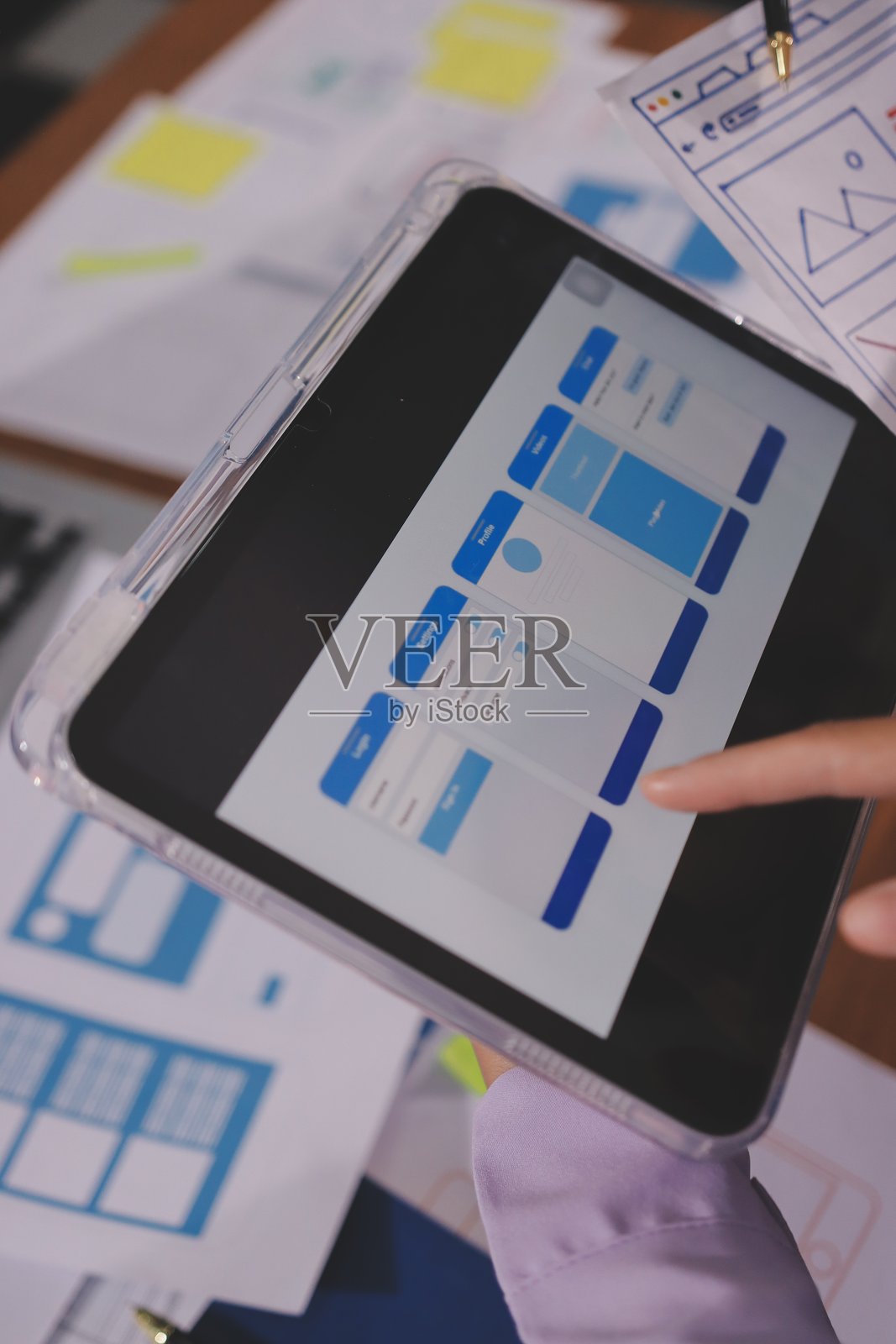 特写：在现代办公室里，用户体验开发人员和用户界面设计师正在桌边就手机应用界面线框图设计、客户简报和色号进行头脑风暴。创意数字开发公司。照片摄影图片