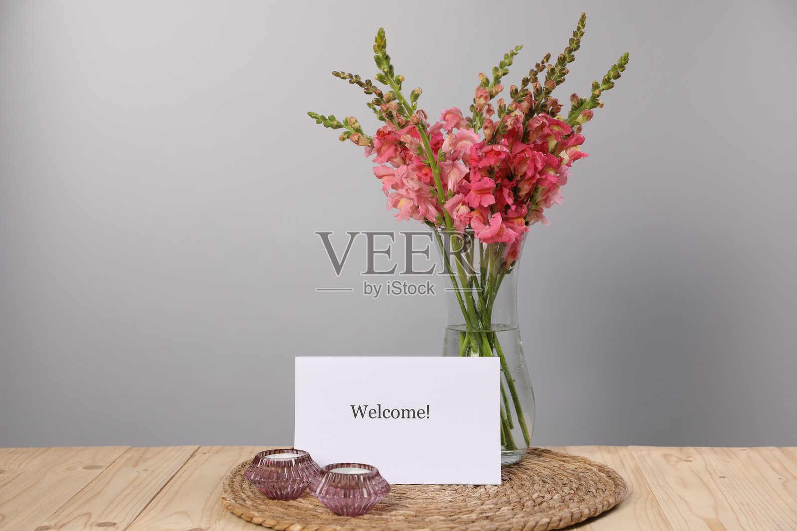 木桌上的“欢迎”卡片、蜡烛和美丽的花朵，留有文字空间照片摄影图片