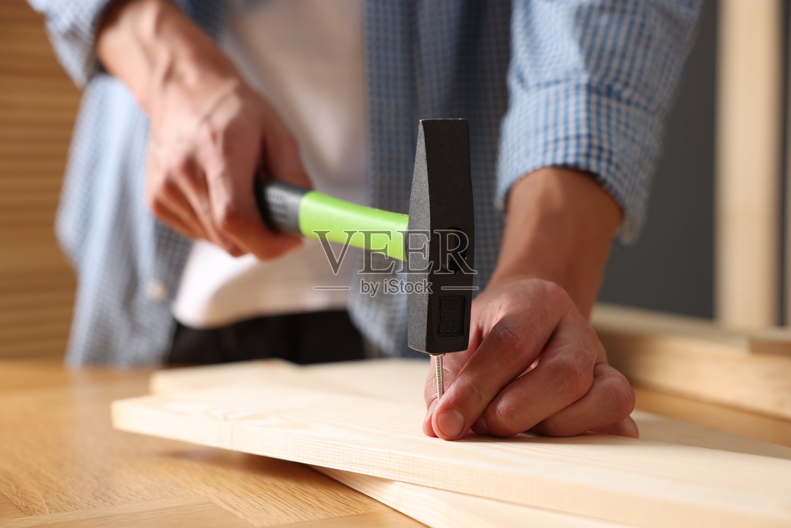 特写：男子在室内将钉子钉入木板照片摄影图片