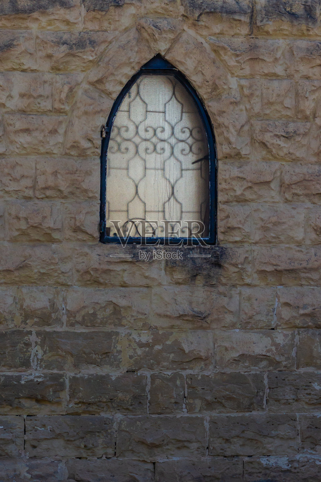 外观建筑上带有拱形窗户和装饰性铁艺栏杆的质朴石墙照片摄影图片