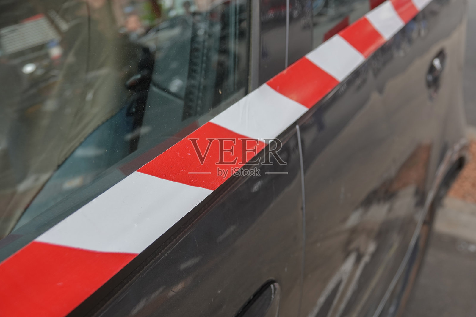 灰色汽车，车窗和车身上有红白条纹胶带，停在城市街道上照片摄影图片