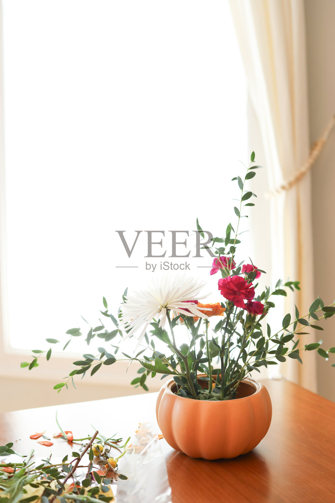 橘色陆莲花、粉色康乃馨，搭配现代南瓜造型花瓶照片摄影图片