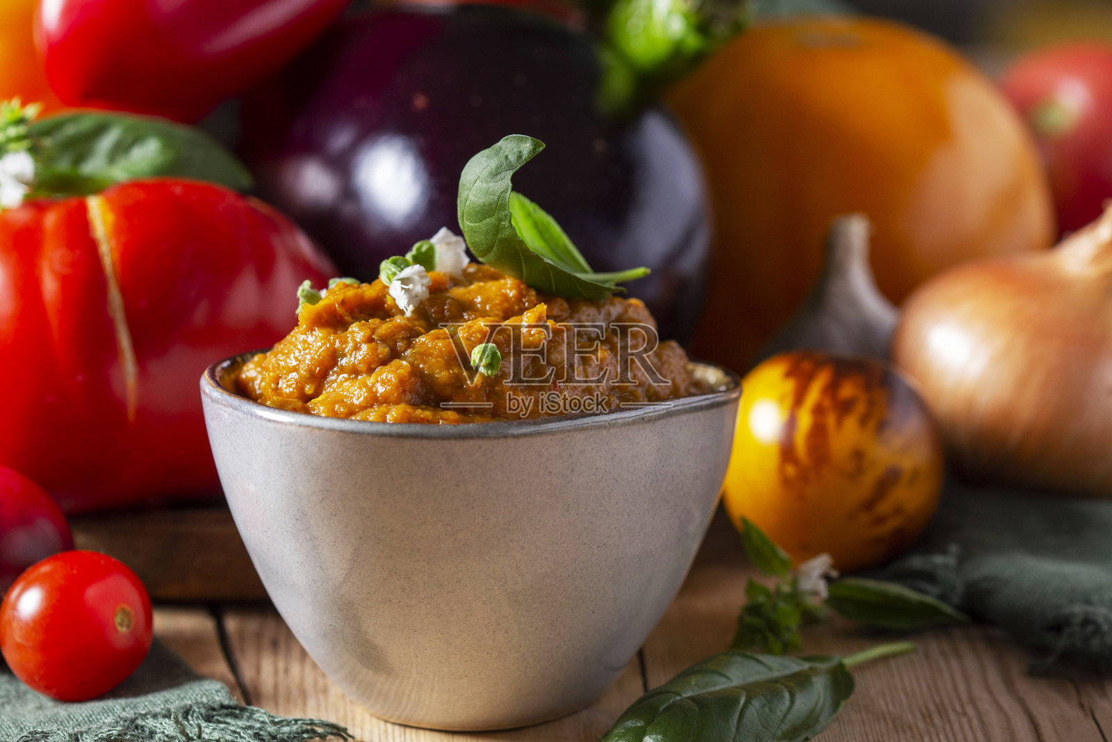 玻璃罐中的茄子鱼子酱和木制背景上的蔬菜。照片摄影图片