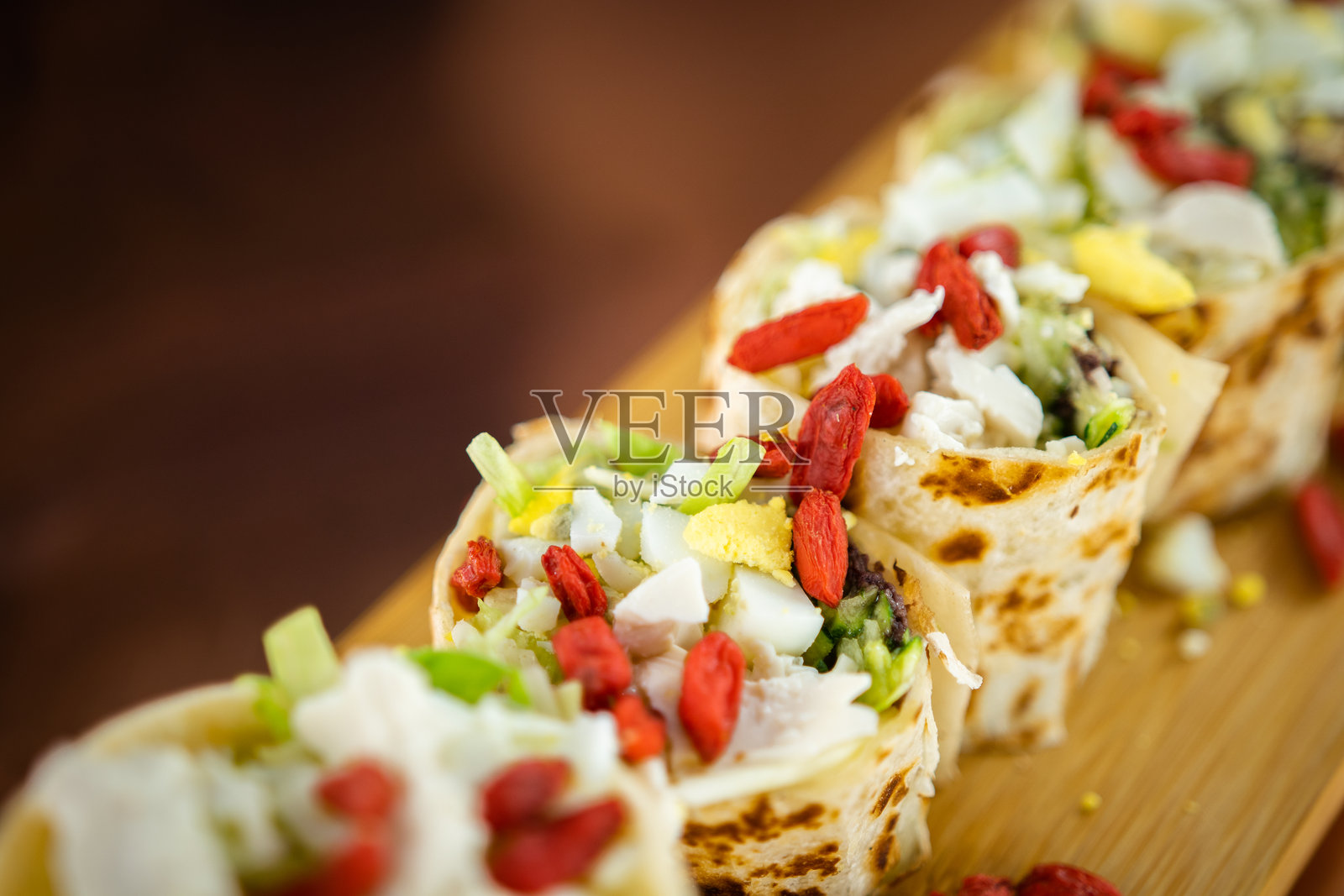 半切的卷饼，内有生肉末、新鲜生菜和奶油芥末酱，置于乡村木质表面上，高清美食摄影照片摄影图片