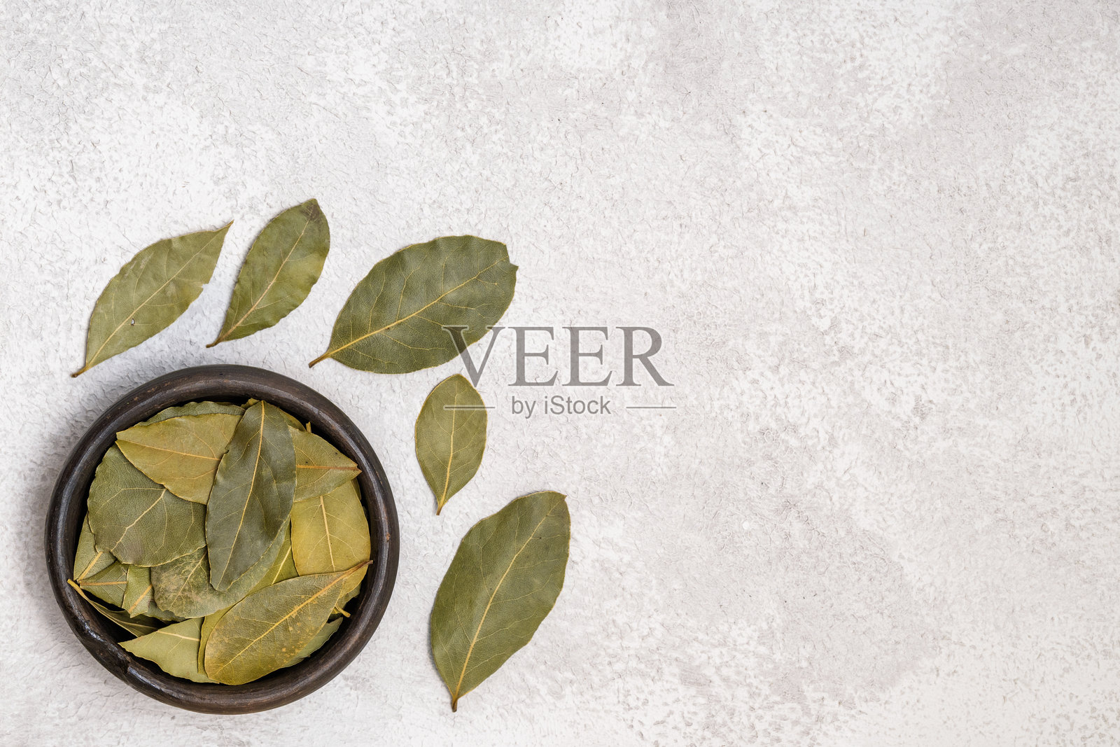 质朴碗中干月桂叶，背景为灰色照片摄影图片