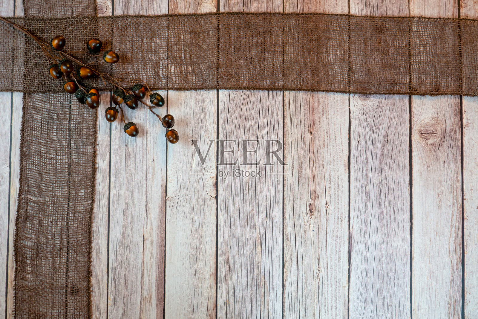 一个带有橡子的棕色丝带 draped 在木质表面上照片摄影图片