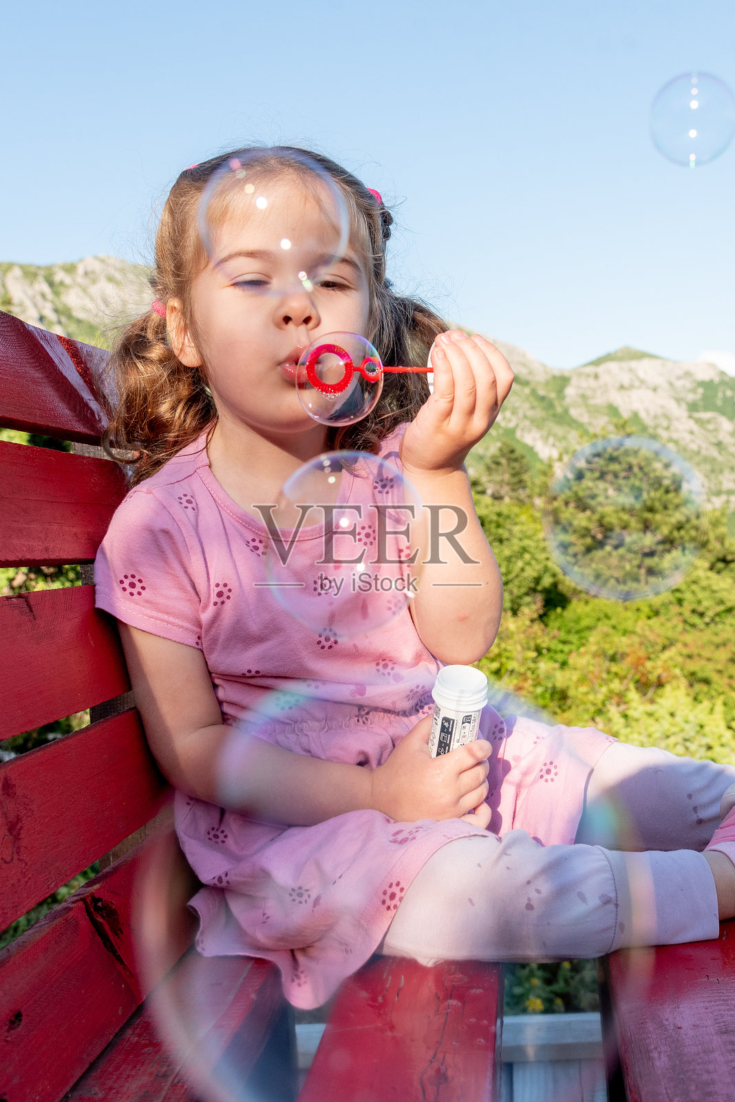 可爱有趣的幼儿小女孩在公园夏日户外吹泡泡照片摄影图片