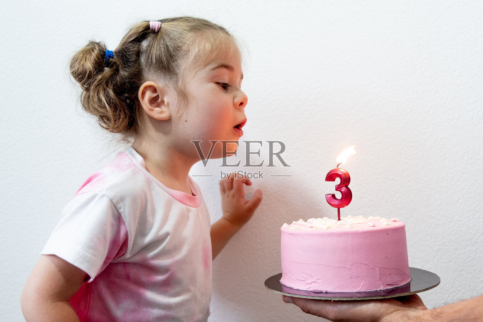 可爱有趣的幼儿小女孩吹灭生日蜡烛数字3粉色蛋糕照片摄影图片