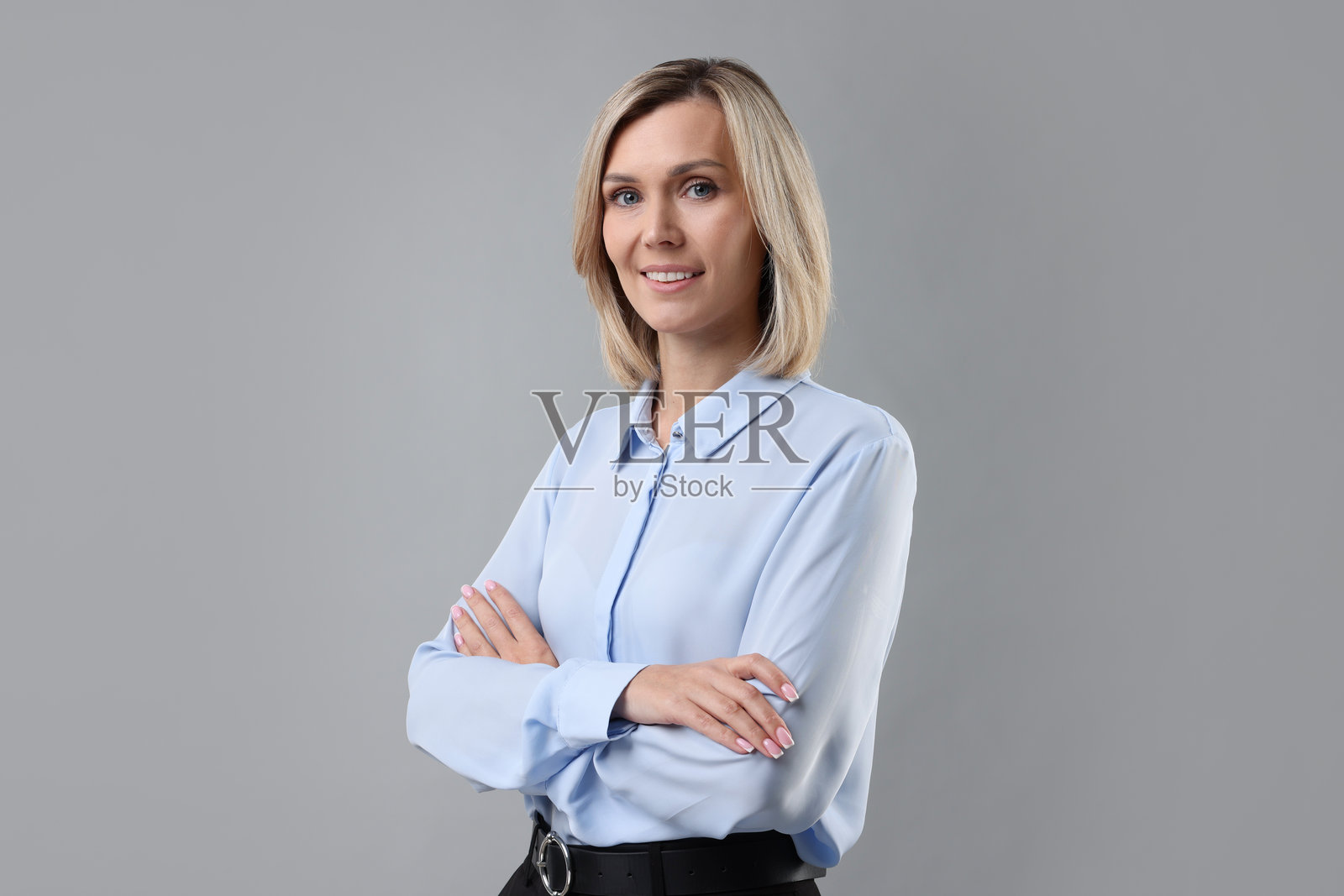 浅蓝色衬衫女商人的肖像，背景为灰色。照片摄影图片